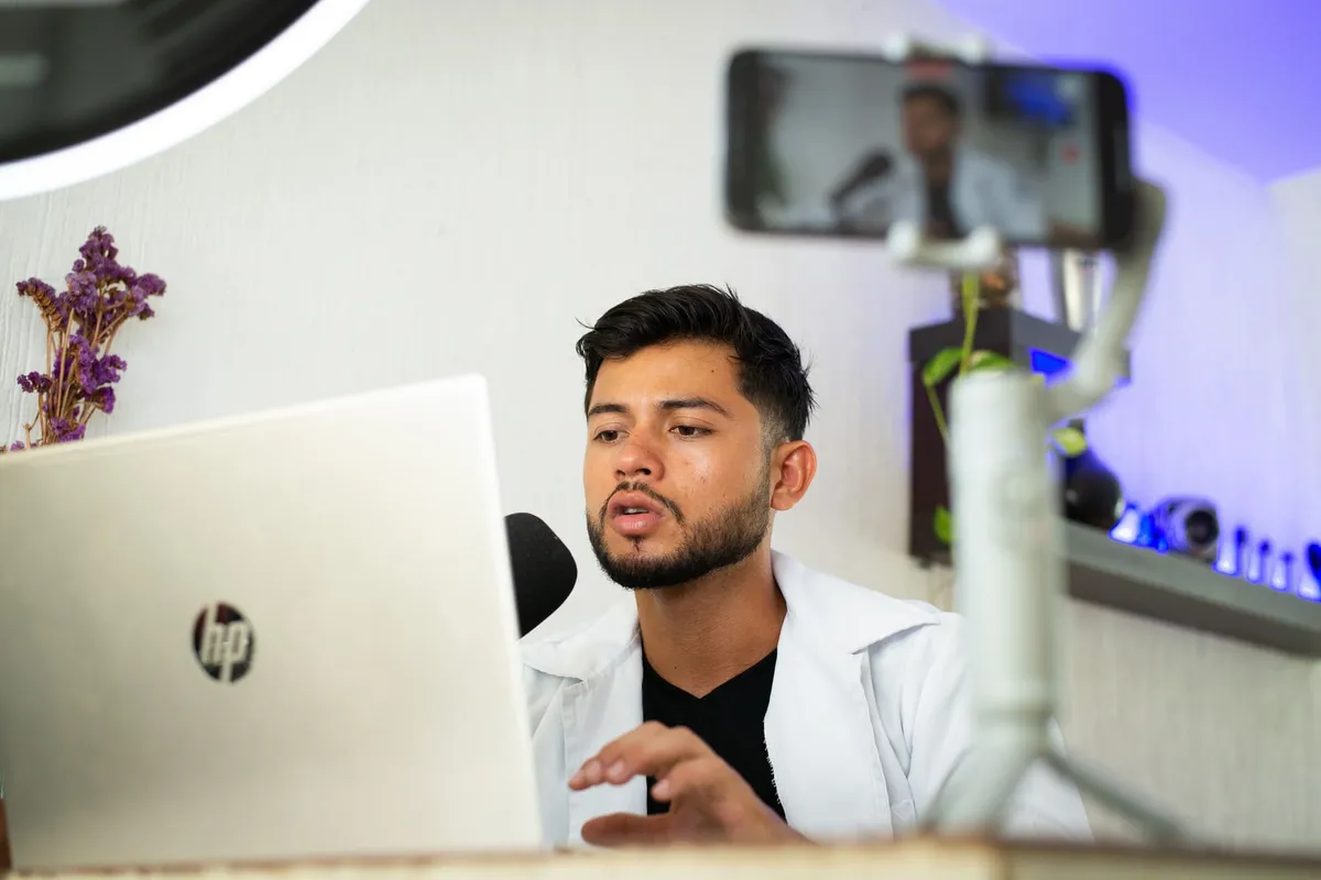 A creator records at his desk with a phone and microphone.
